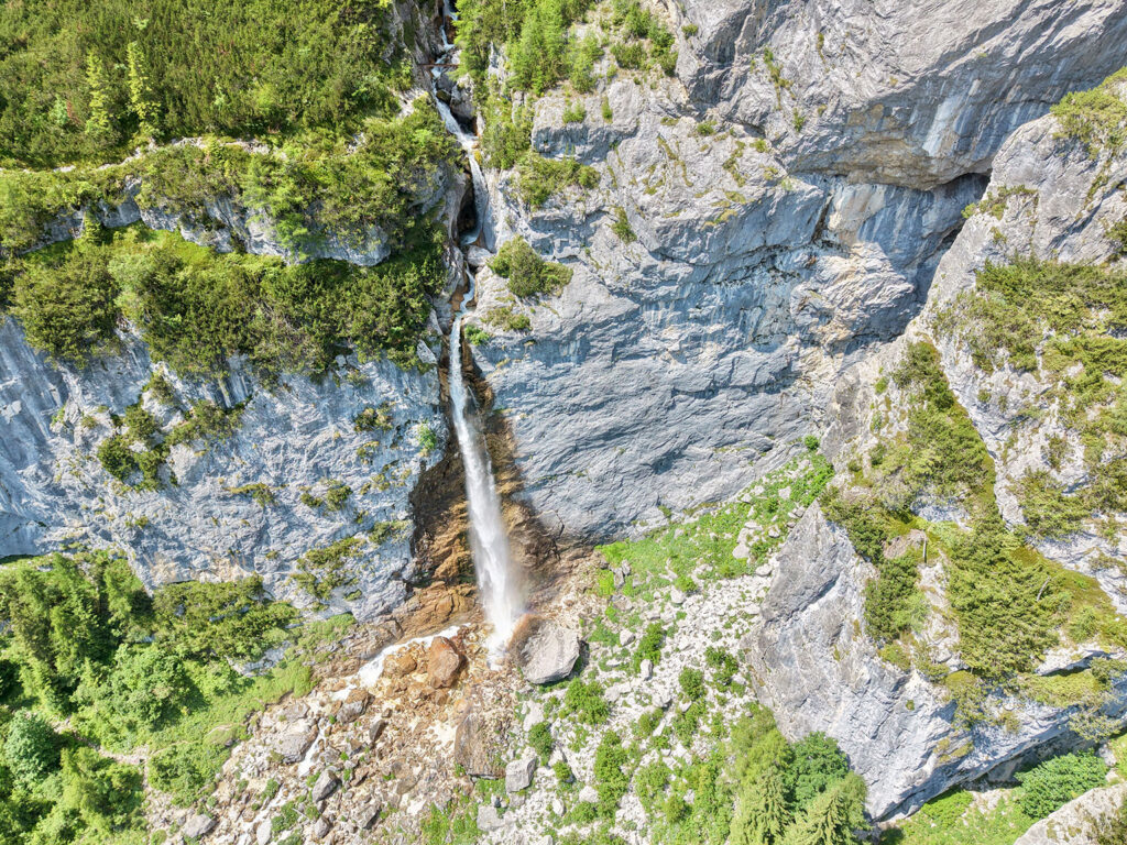Wasserfall von Gares zwischen steilen grauen Felswänden und grünen Hängen.