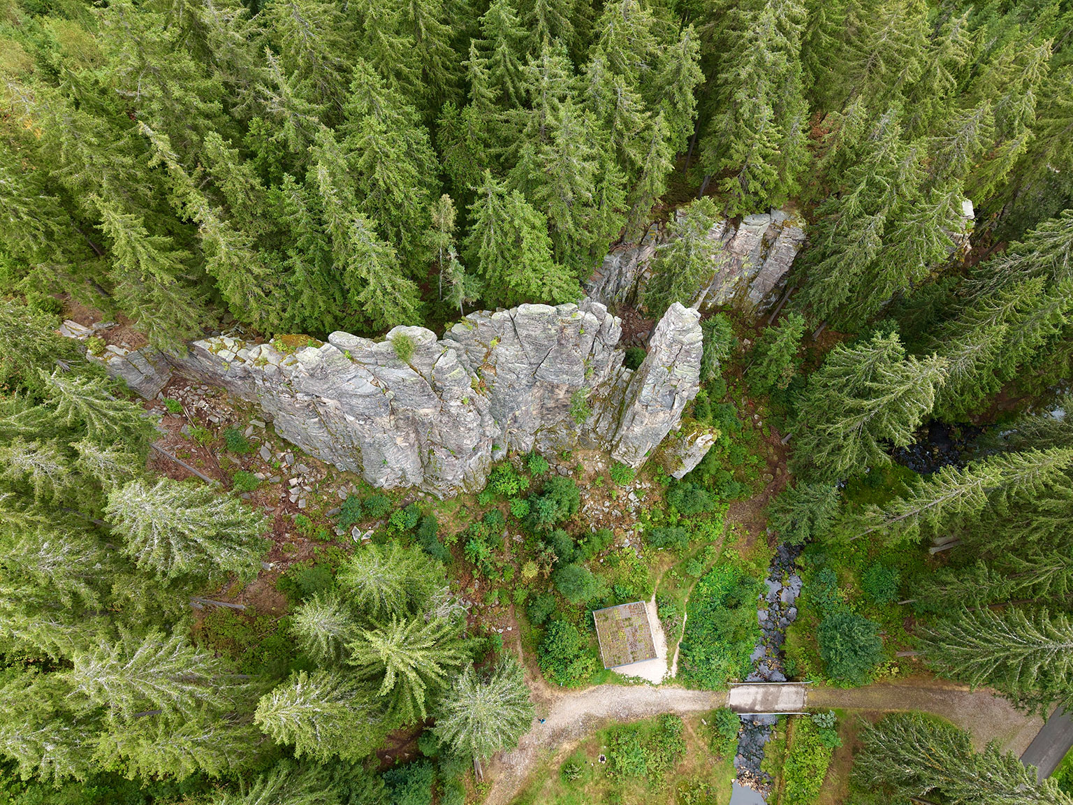Luftaufnahme markanter Felsen im Wald bei Erlabrunn mit Bach, Brücke und Wanderweg.
