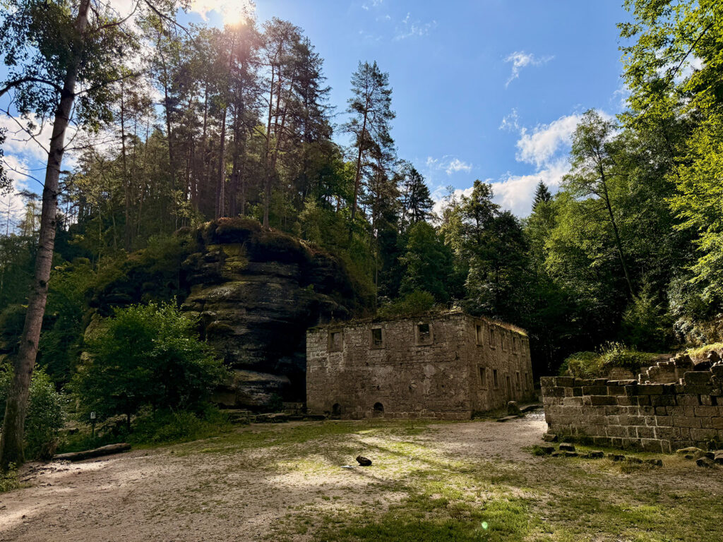 Ruine Dolský mlýn zwischen bewaldeten Felsen in der Böhmischen Schweiz.
